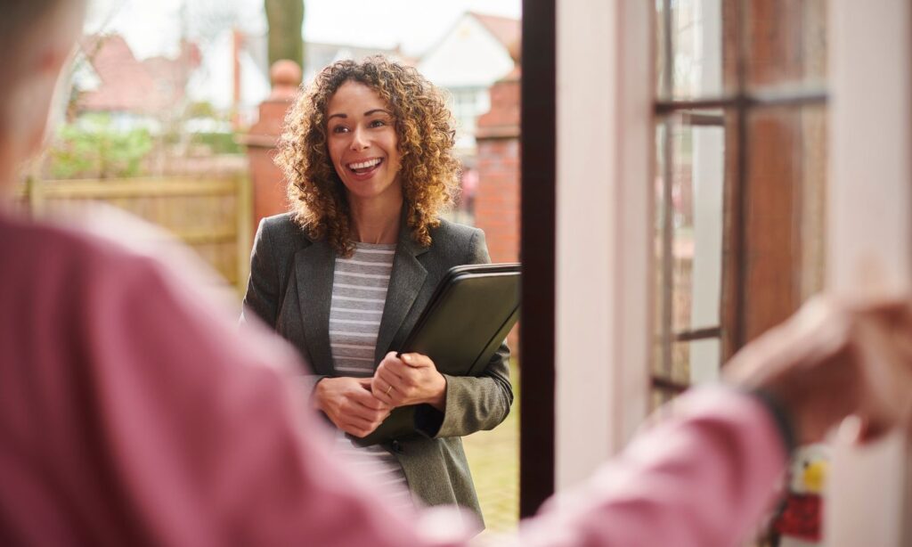 Landlord with a folder smiling at a tenant during a home visit.
