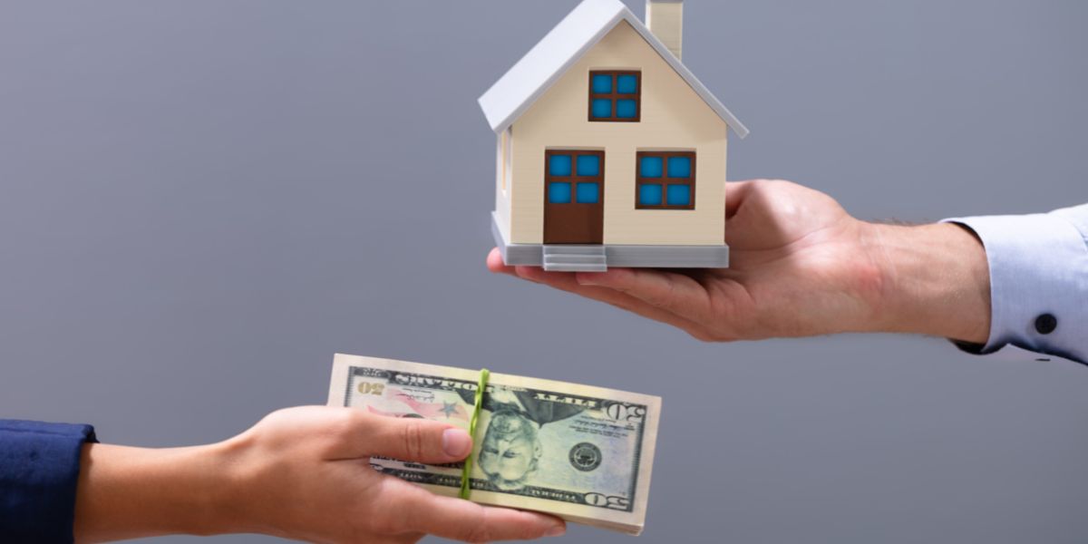 Person exchanging a house model for a stack of US dollar bills.