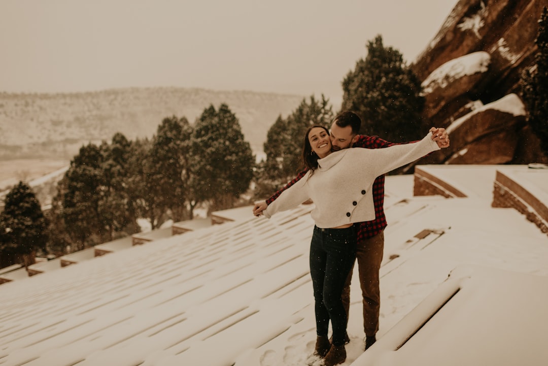 Smiling couple stands proudly in front of their contemporary home in Denver, representing the financial success and satisf...