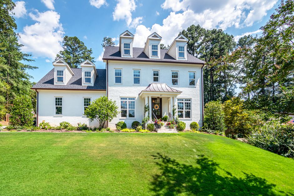 The beautiful exterior of a modern suburban home in St. Tammany with a welcoming porch and manicured lawn, representing a valuable property being sold smartly with a low-commission realtor.
