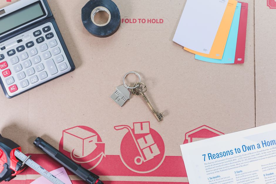 A clean, modern desk with house keys, a calculator, and a pen, symbolizing the smart financial calculations involved in saving on realtor commissions when selling a home.