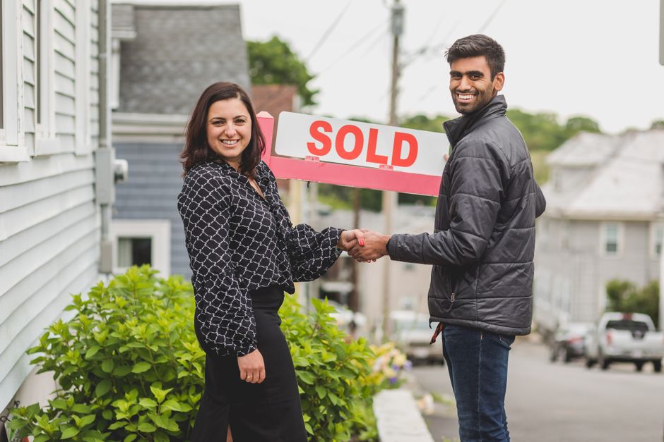 A 'Sold' sign in the front yard of a welcoming home, with the charming neighborhood street blurred softly in the background, signifying a successful transition and a positive future for the community.