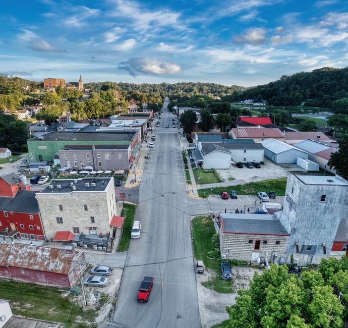 A vibrant and sunny main street in a small town, with people walking past thriving local shops and businesses, representing local economic growth and community vitality.